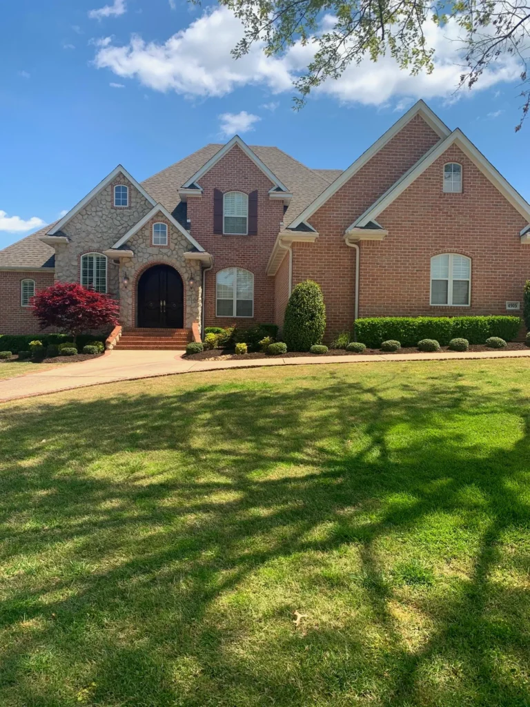 Arkansas home with freshly mowed lawn, landscaped bushes, and a Japanese maple tree